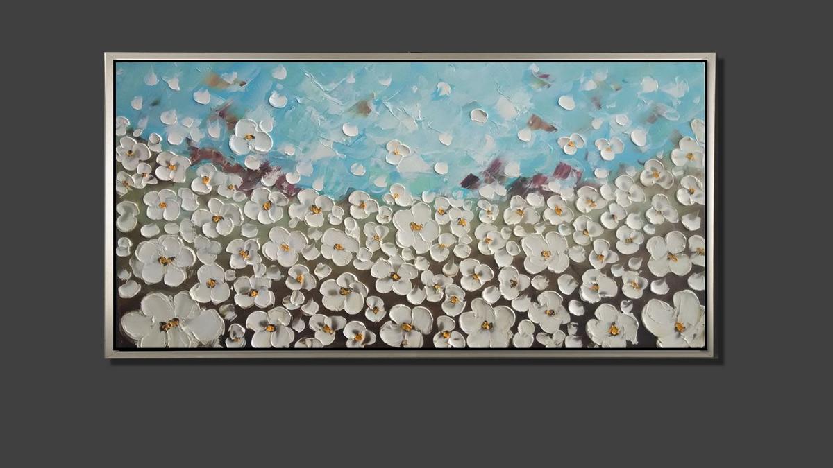 Handgemaltes Ölbild weisse Blütenwiese auf Leinwand, reliefartige Spachtelblüten unter hellblauem Himmel, mit silbernem Rahmen – Beispiel im Raum