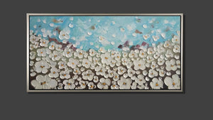 Handgemaltes Ölbild weisse Blütenwiese auf Leinwand, reliefartige Spachtelblüten unter hellblauem Himmel, mit silbernem Rahmen – Beispiel im Raum