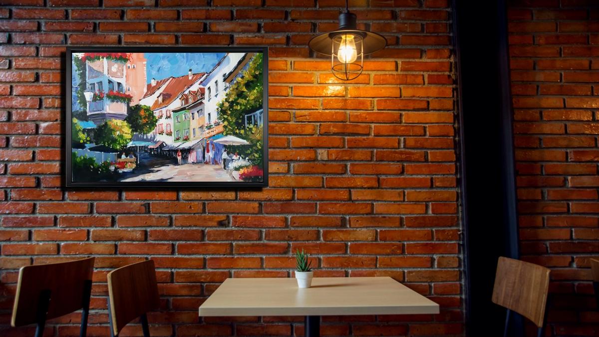 Handgemaltes Ölbild bunte Altstadtgasse mit Cafés auf Leinwand, farbenfroh mit Spachtel gemalt, mit schwarzem Rahmen – Beispiel im Raum