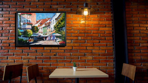 Handgemaltes Ölbild bunte Altstadtgasse mit Cafés auf Leinwand, farbenfroh mit Spachtel gemalt, mit schwarzem Rahmen – Beispiel im Raum