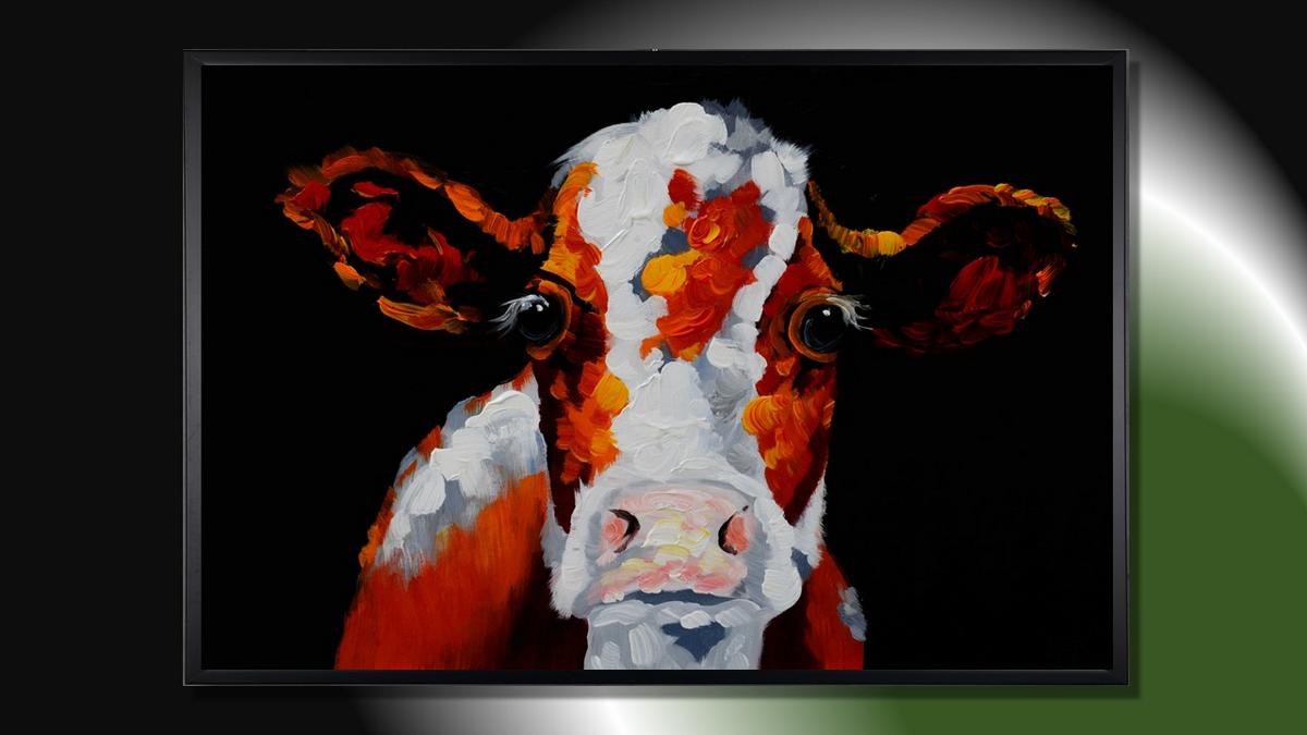 Handgemaltes Ölbild bunte Kuh auf Leinwand, orange-rote Flecken mit Spachtelrelief vor schwarzem Hintergrund, mit schwarzem Rahmen – Beispiel im Raum