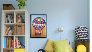 Handgemaltes Ölbild Heissluftballon mit Kindern auf Leinwand, rot-blau-gelbes Karomuster, heller Himmel, mit schwarzem Rahmen – Beispiel im Raum