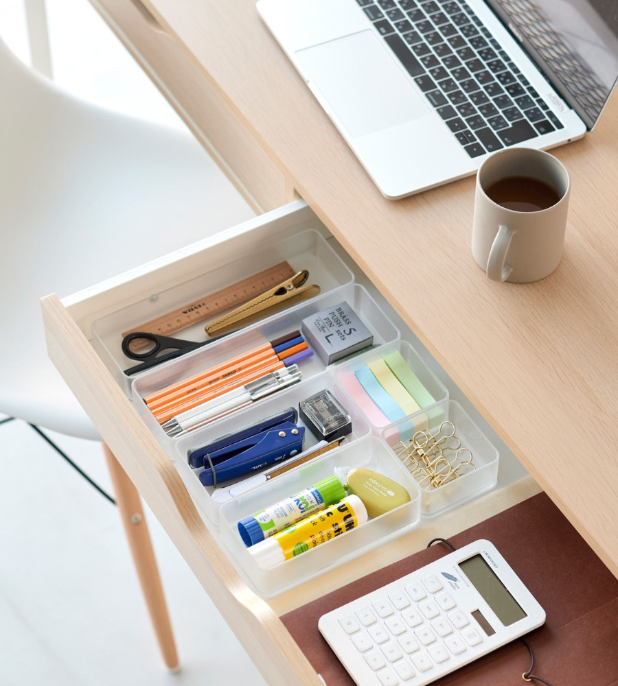 Eine aufgeräumte Schreibtischschublade mit dem YAMAZAKI TOWER Schubladen Organizer Weiss M (2er Set) bewahrt Stifte, Bleistifte, Schere, Lineal, Haftnotizen, Büroklammern, Hefter, Klebestift, Radiergummi und Taschenrechner neben Laptop und Tasse auf einem hellen Holzschreibtisch ordentlich auf.