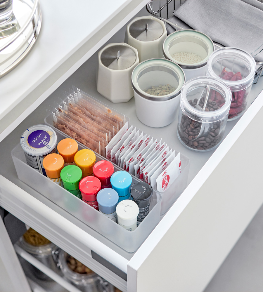 Eine geordnete Küchenschublade mit dem YAMAZAKI TOWER Schubladen Organizer Weiss L DEEP (2er Set), in der Gewürzdosen, Päckchen und stapelbare Behälter für Bohnen und Körner sowie ein paar weiße Deckelbehälter ordentlich aufbewahrt werden.