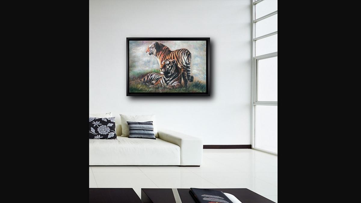 Handgemaltes Ölbild Tigerpaar auf Leinwand, stehender und liegender Tiger im Gras vor hellem Hintergrund, mit schwarzem Rahmen – Beispiel im Raum