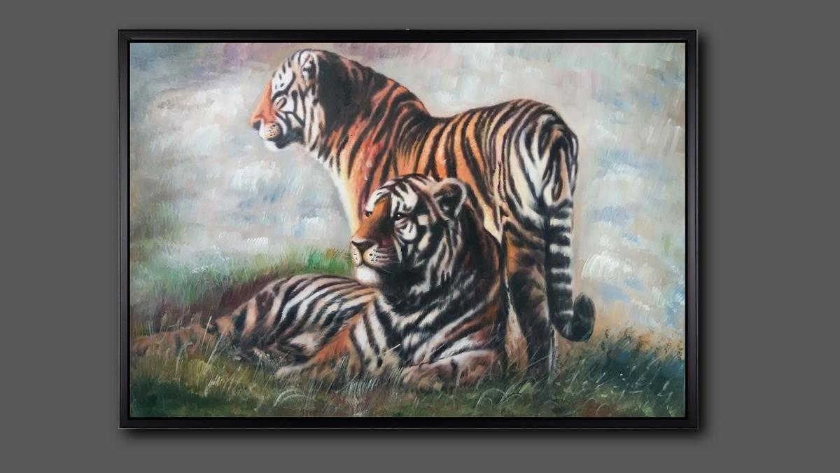 Handgemaltes Ölbild Tigerpaar auf Leinwand, stehender und liegender Tiger im Gras vor hellem Hintergrund, mit schwarzem Rahmen – Beispiel im Raum