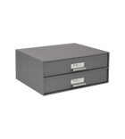 Graue Pappschubladenbox mit Metallschildern zur Organisation im Büro.