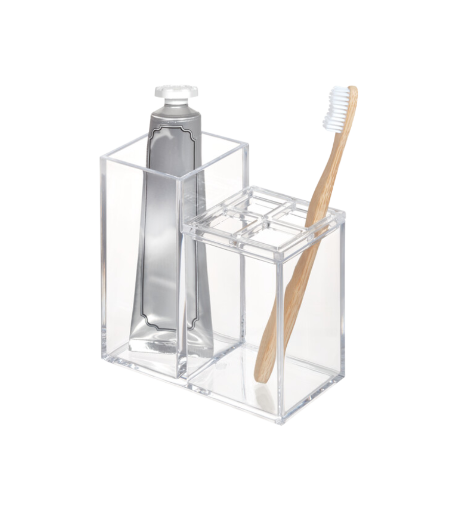 Der iDesign CLARITY - Kosmetik Organizer KLAR II, ein klarer Acrylhalter, bewahrt eine Zahnpastatube und eine Bambuszahnbürste mit weißen Borsten übersichtlich auf - eine ideale Bad Aufbewahrungslösung auf einem schlichten weißen Hintergrund.